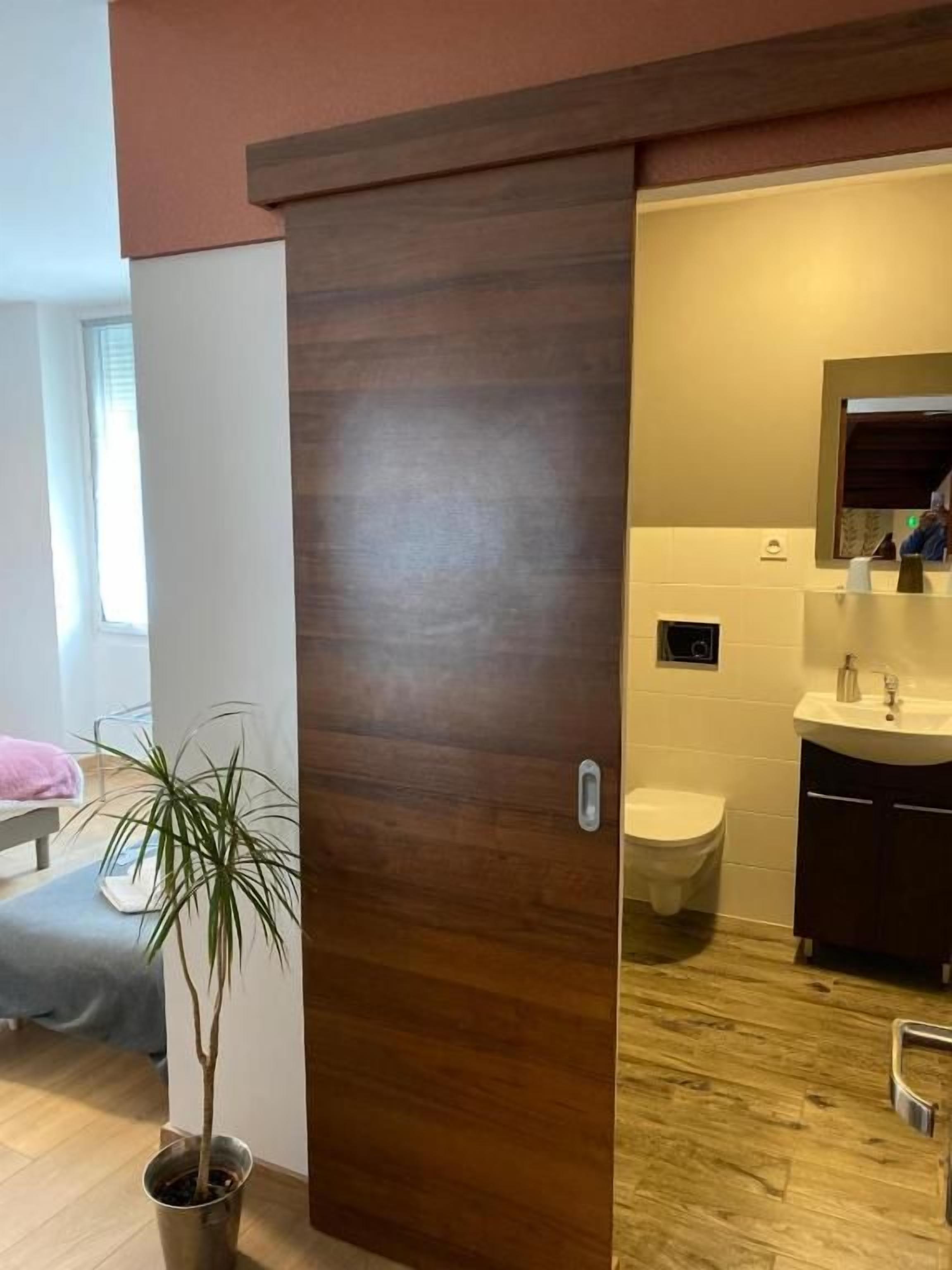 A bathroom with a wooden door, a sink, and a toilet.