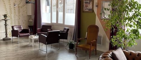 Una sala moderna con piso de madera en patrón de espiga, sofás de cuero, una mesa de comedor con sillas e iluminación colgante.