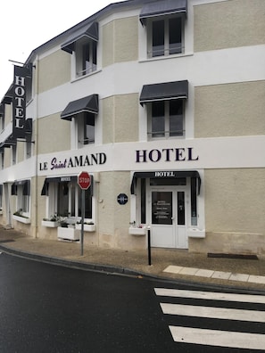 Ein Hotel namens 'Le Saint Amand' mit einem Stoppschild davor, einem Fußgängerüberweg und freiem Blick auf den Eingang.
