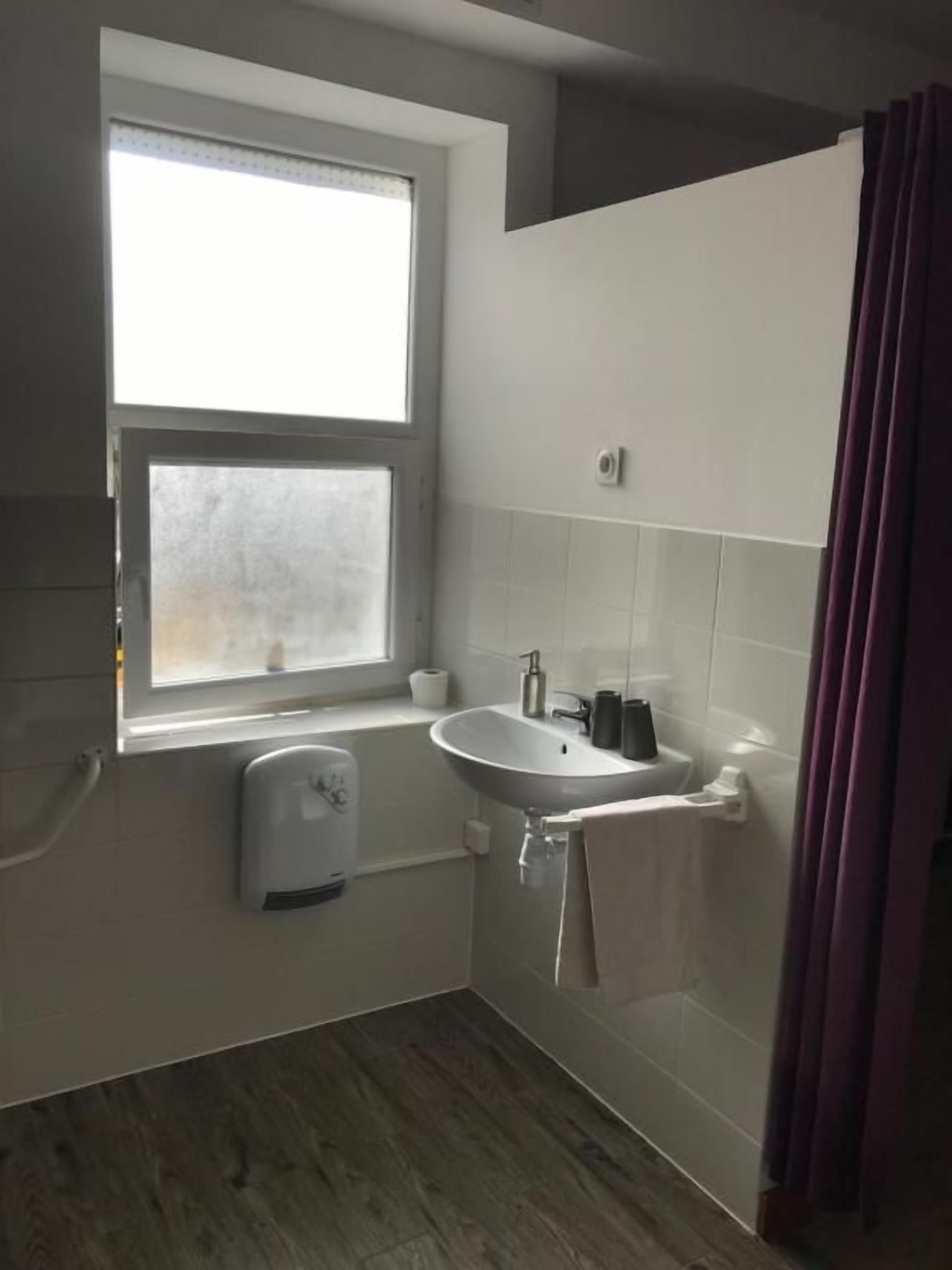 A bathroom with a window, a sink, and a shower.