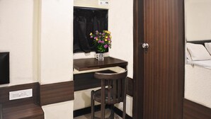 A compact kitchenette with a small table, a chair, and a window with flowers. - a1 Hotel (Mumbai)