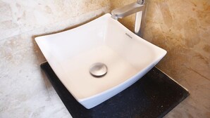 A white square sink with a single basin and a modern faucet, set against a textured beige wall. - a1 Hotel (Mumbai)