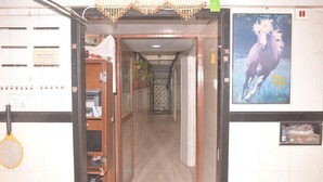 A hallway with a wooden door, a poster of a horse, and a sign on the wall. - a1 Hotel (Mumbai)