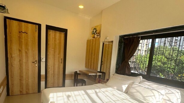 A bedroom with a bed, a desk, and a window with a view. - a1 Hotel (Mumbai)