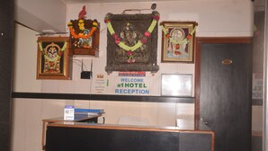 A hotel reception area with a reception desk, framed pictures, and a welcome sign. - a1 Hotel (Mumbai)