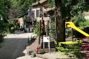 A playground with a yellow slide, a climbing structure, and a small table with chairs. - Chalets Bois Moulin de Chaules (Saint-Constant-Fournoulès)