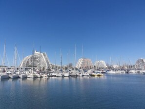 A marina with multiple boats docked, surrounded by modern buildings.