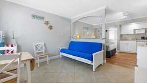 A compact living space with a kitchenette, a dining area, and a seating area with a blue sofa.