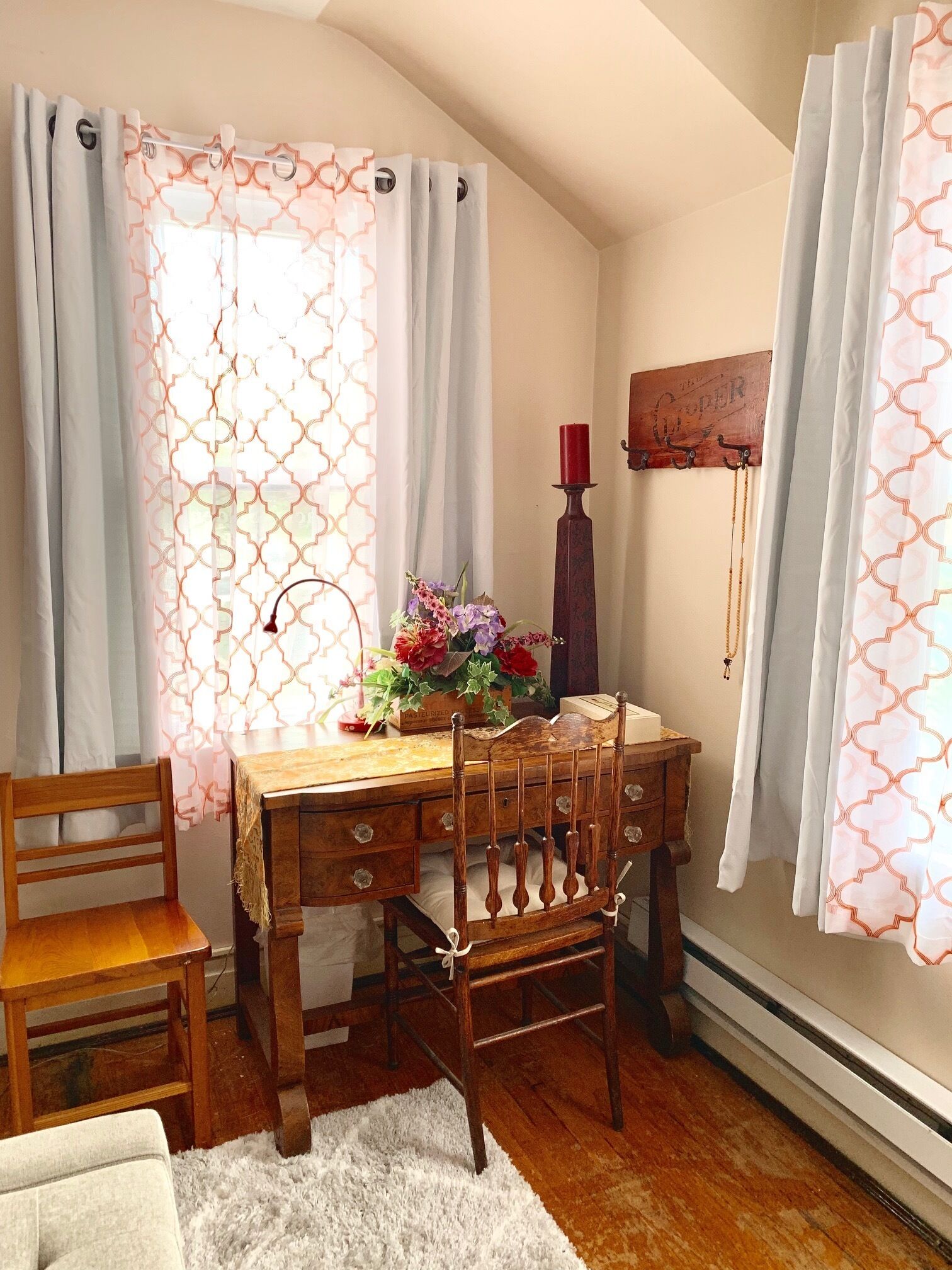 A cozy dining area with a wooden table and chairs, a vase of flowers, and a candle holder on the wall.