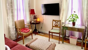 Ett vardagsrum med en tv, två fåtöljer, ett bord med en växt och en röd lampa.