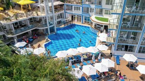 A multi-level hotel with a central swimming pool surrounded by sun loungers and umbrellas. - Villa List Hotel (Sozopol)