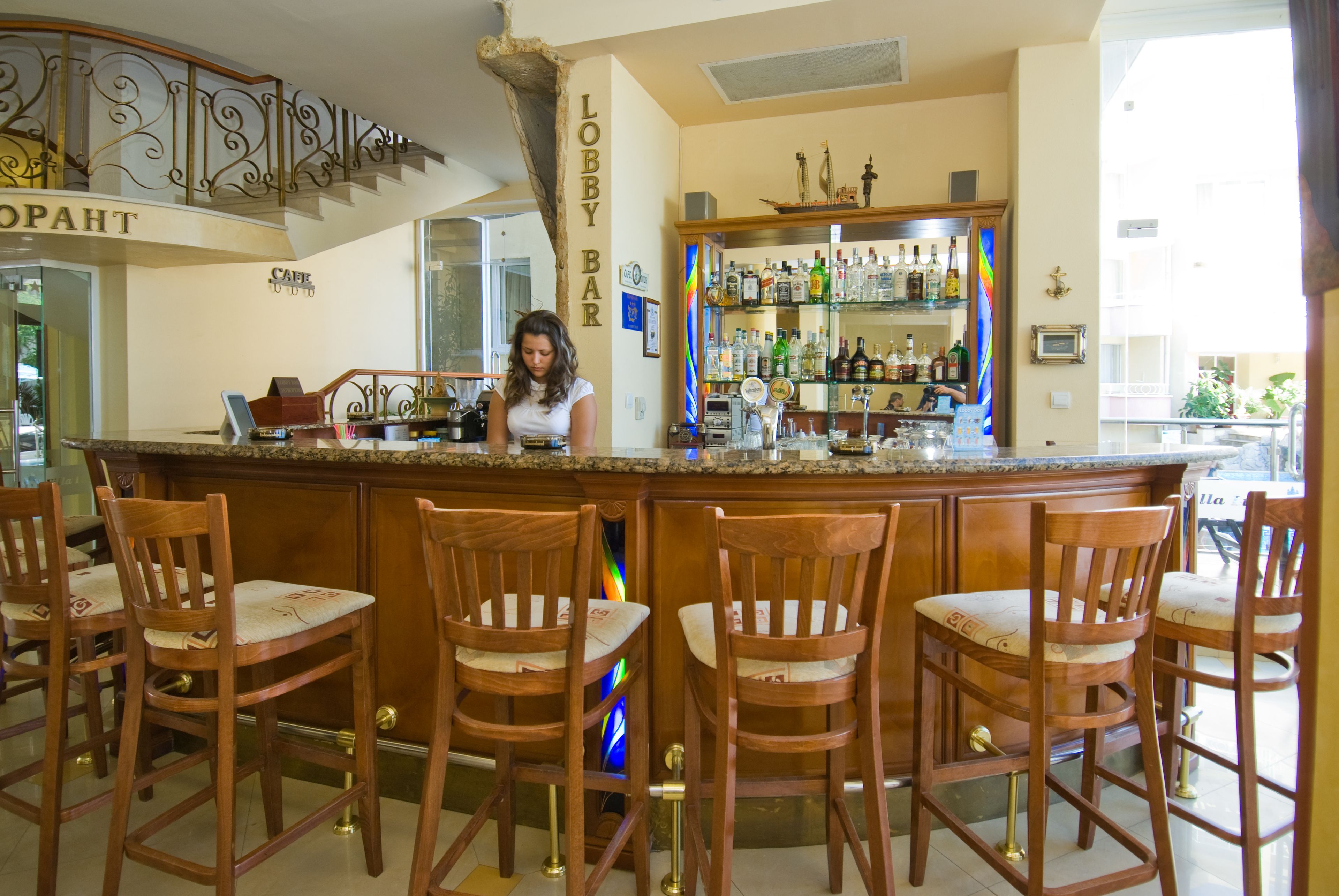 A bar area with wooden chairs, a bar counter, and a variety of bottles.