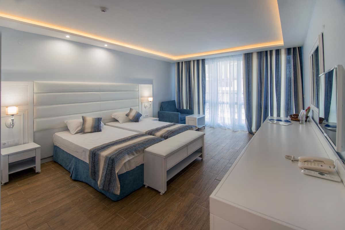 A modern hotel room with a large bed, bedside tables, a desk, and a chair.