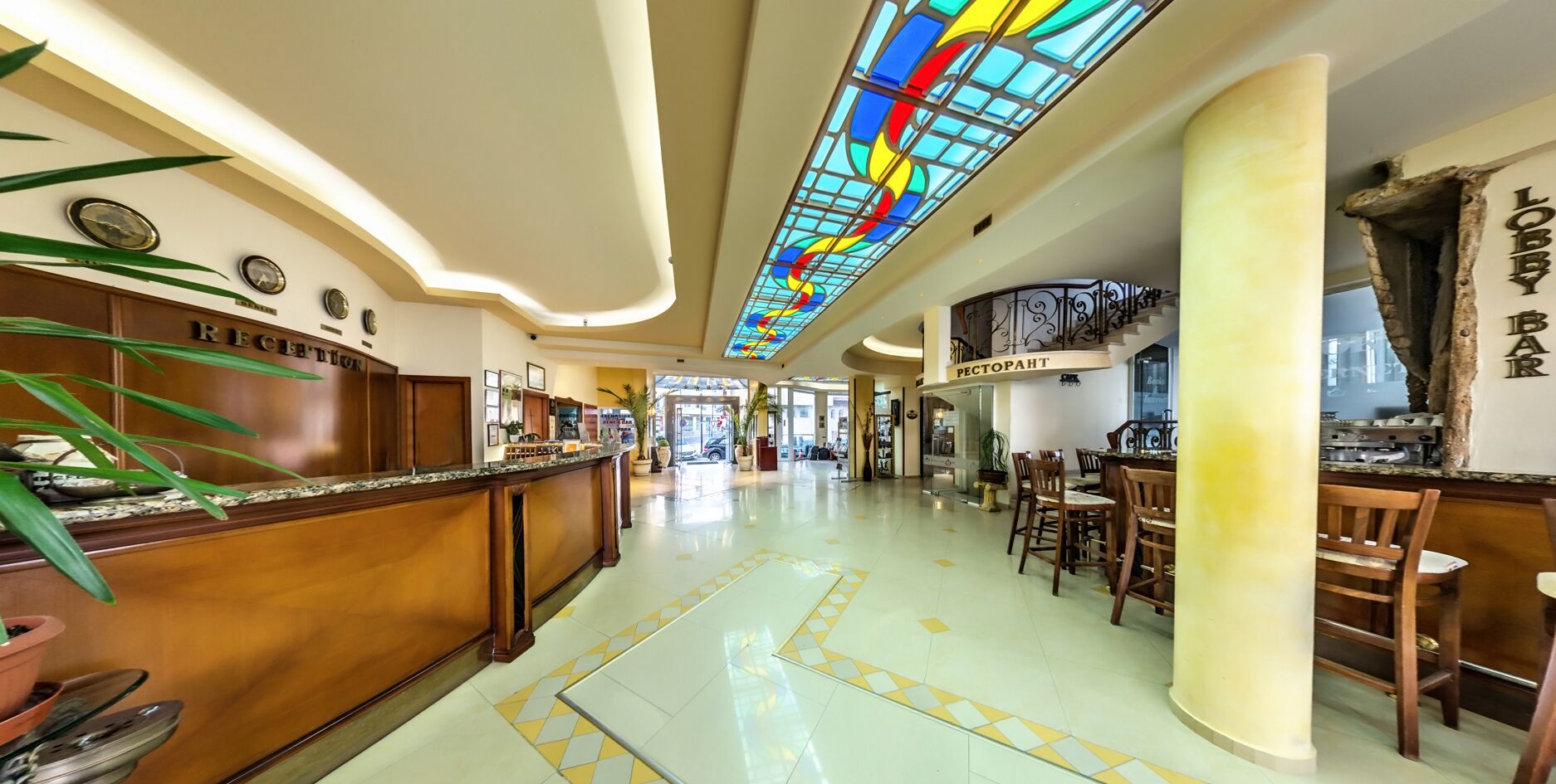 Een hotellobby met een receptiebalie, een trap en een bar.