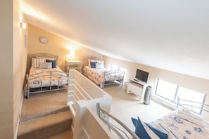 A bedroom with two beds, a TV, a heater, and a window.