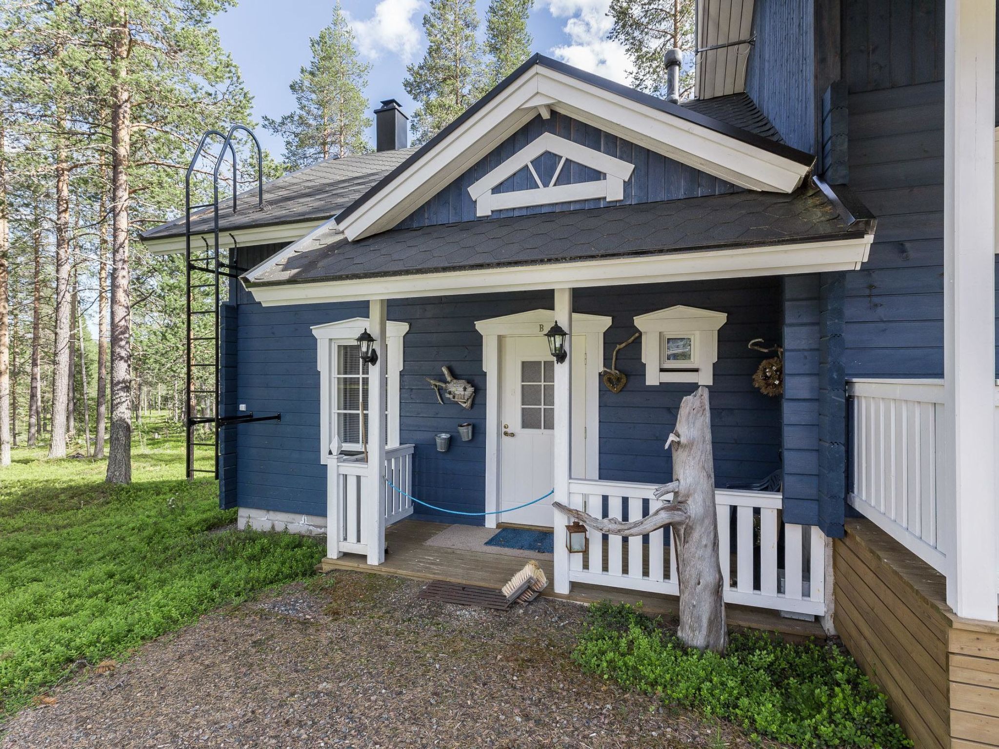 Et blåt hus med veranda, dør og postkasse.