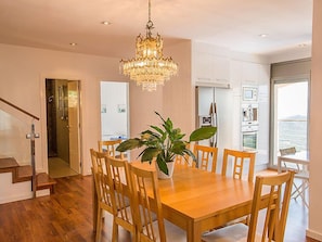Un espace repas moderne avec une table et des chaises en bois, un lustre et une plante en pot.