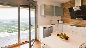 Una cocina moderna con un ventanal grande, un lavavajillas y un frutero sobre la mesa.