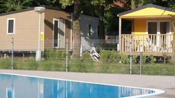 A swimming pool with a fenced area, a small wooden structure, and a metal fence.