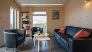 Un salon moderne avec un canapé en cuir noir, un fauteuil noir, une petite table en bois et une bibliothèque.