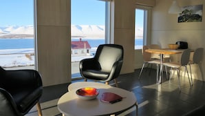 Une chambre moderne dotée de grandes fenêtres, d’un coin repas et offrant une vue sur des montagnes enneigées.