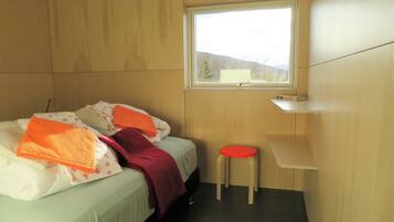 Een kamer met twee bedden, een raam en een klein krukje.
