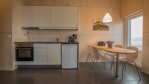 Une cuisine moderne équipée d’un four encastré, d’une machine à café et d’un coin repas avec une table et des chaises.