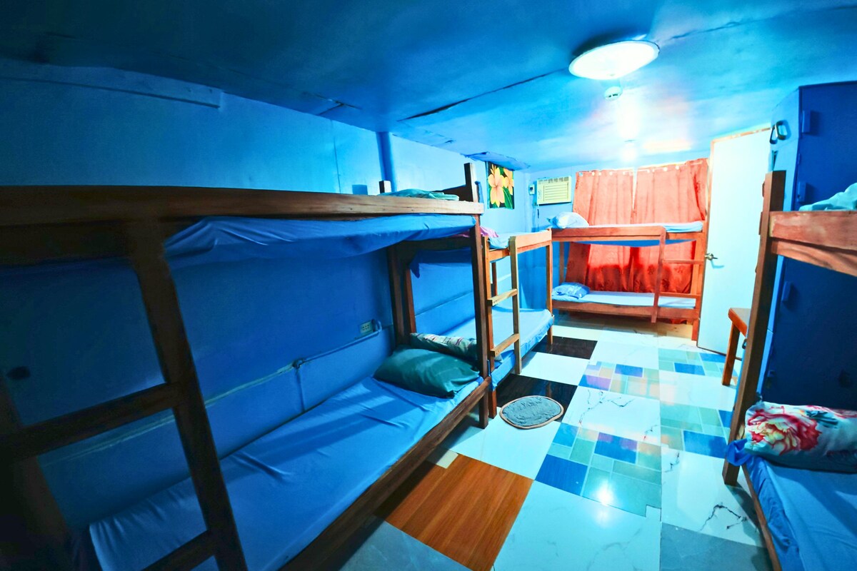 Un dormitorio con literas, suelo de baldosas y ventilador de techo.