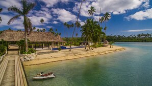 A beach resort with a thatched-roof hut, a wooden deck, and a clear blue sea. - WAVI Paradise, Private Luxury Island - 1 to 6 guests (Savusavu)