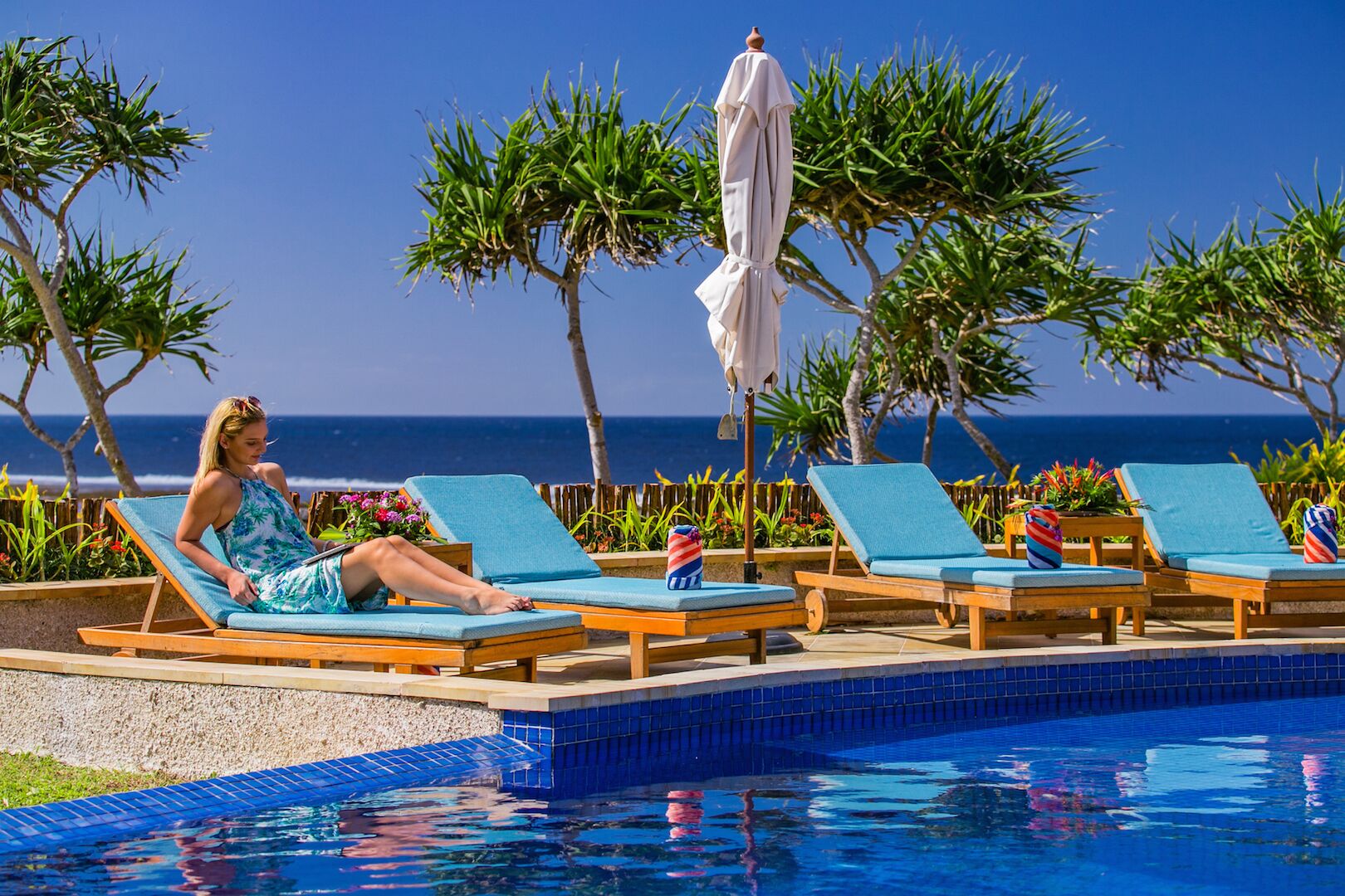 Un espace aménagé au bord de la piscine, avec des chaises longues, une piscine et une vue sur l’océan.