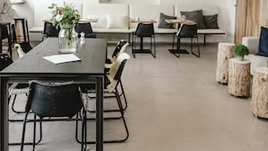 A modern meeting room with a long table, chairs, a vase with flowers, a sofa, and a wall-mounted plant. - Wake Up Wellness Hostel by goodnite cz (Brno)