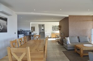 Una sala de estar moderna con una mesa de comedor de madera, sillas, un sofá gris y una mesa de centro.