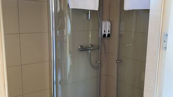 Une cabine de douche fermée par des parois en verre, dotée d’un pommeau de douche à main et d’un porte-serviettes.