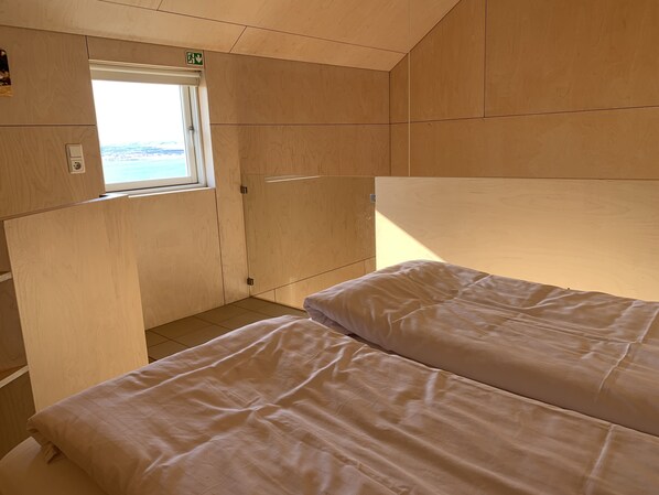 A cabin with two beds, a window, and wooden walls.