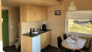 A compact kitchen with wooden cabinets, a sink, and a dining area with a table and chairs. - Sunnuhlid houses (Akureyri)