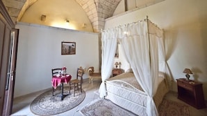 Une chambre à coucher avec un lit à baldaquin, une table ronde avec des chaises et une petite table de chevet.