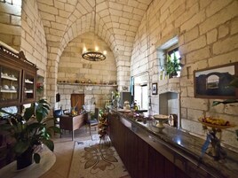 Cocina de paredes de piedra con techo alto, una isla central y una zona de bar con una exhibición de frutas.