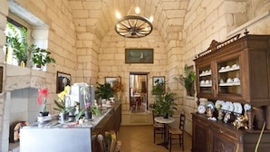 Une cuisine aux murs de pierre, dotée d’un îlot central, d’un lustre et d’un coin repas avec une table et des chaises.