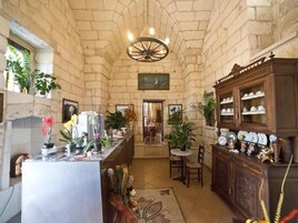 Una cocina con paredes de piedra, una isla central, una araña y un comedor con mesa y sillas.