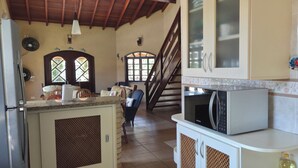 A kitchen with a microwave, cabinets, and a staircase leading to another level.