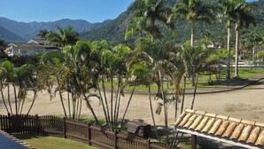 Une plage bordée de palmiers, une clôture en bois et des maisons en arrière-plan.