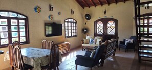 A dining area with a table, chairs, a sofa, and a TV.