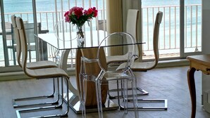 A dining area with a table and chairs, a vase with flowers, and a view of the sea through large windows. - Panoramic view  (La Baule-Escoublac)
