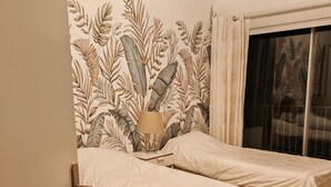 A bedroom with two single beds, a wooden floor, and a wall with a leaf pattern. - Panoramic view  (La Baule-Escoublac)