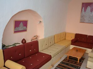 A living room with a sofa set, a wooden coffee table, and a patterned rug. - DAR LILY offers you an authentic and hidden Djerbian experience. (Djerba)