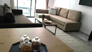 Un salon avec un canapé, une table basse et un téléviseur fixé au mur.
