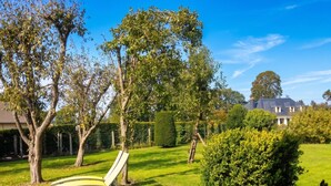 Ein gepflegter Garten mit Rasenfläche, einer gebogenen weißen Bank und einem Haus im Hintergrund.