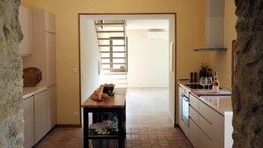 Une cuisine avec une table en bois, un étendoir suspendu et un plan de travail blanc.