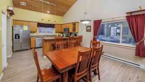 A spacious kitchen with wooden cabinets, a stainless steel refrigerator, a microwave, and a dining area with a wooden table and chairs.