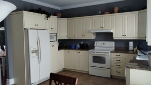 Una cocina con armarios blancos, un refrigerador, un microondas, una estufa y un lavamanos.